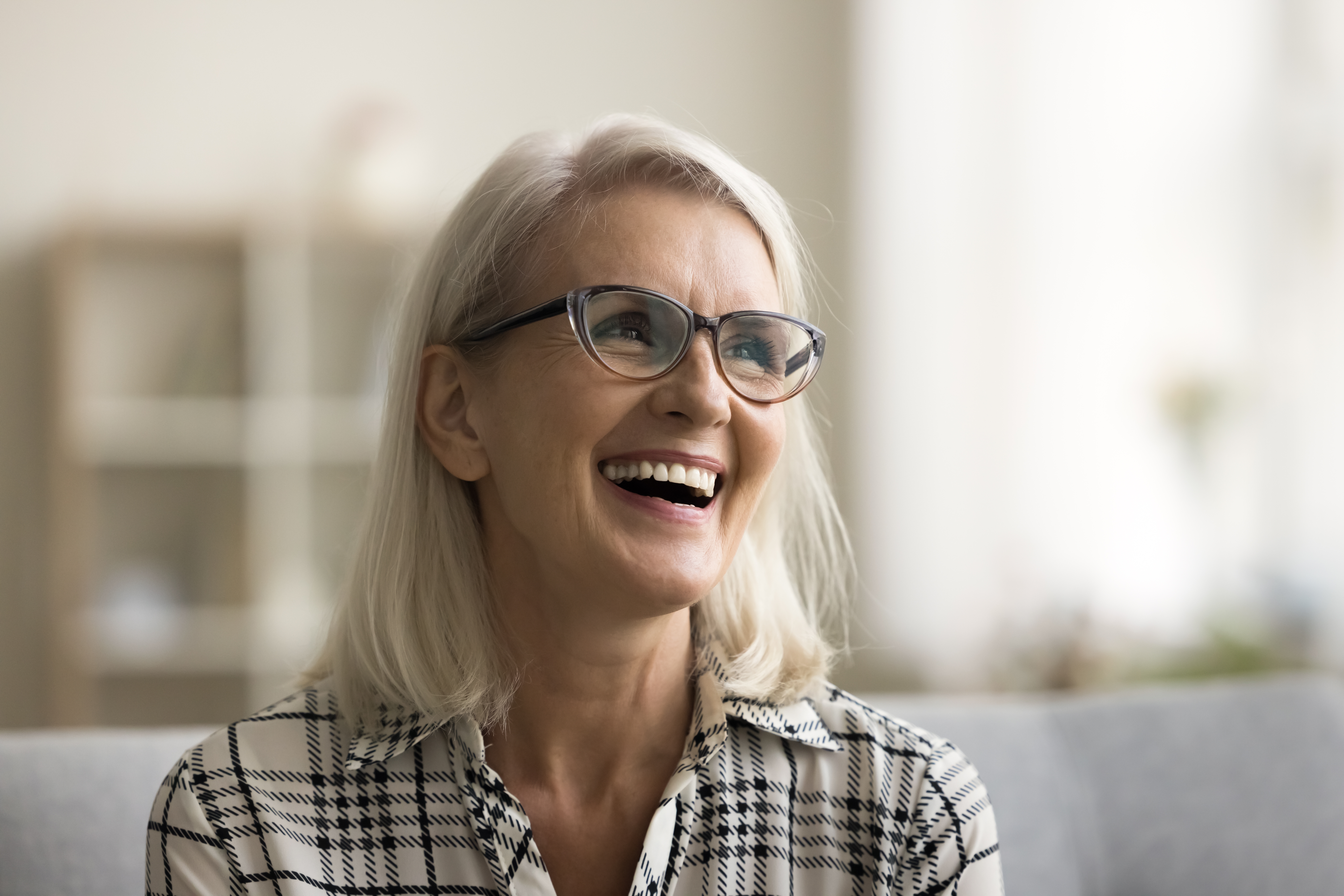 older woman smiling on a couch, new dental implants