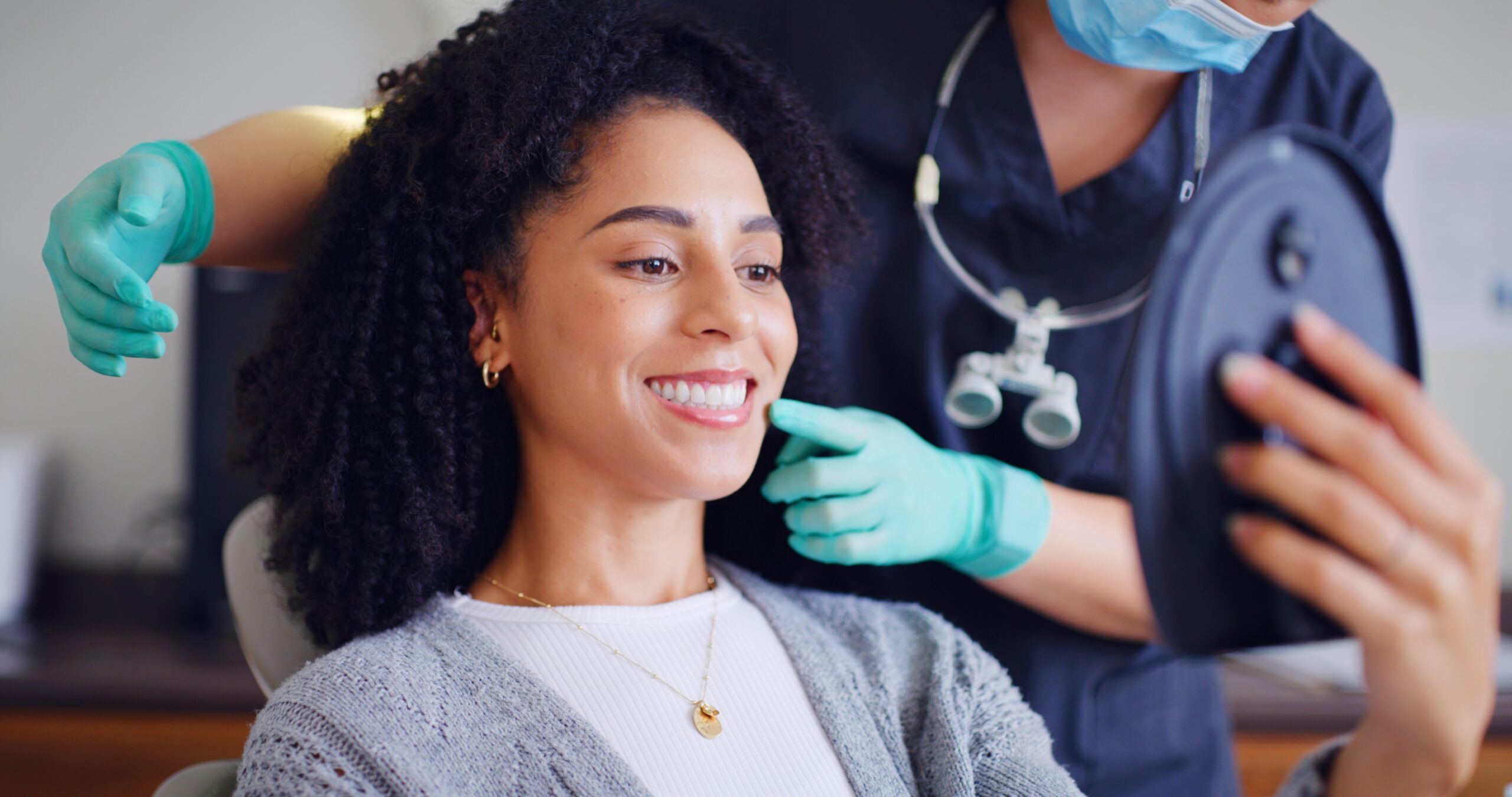 young woman smiling in a dental chair, routine checkup, dentist in green light green gloves