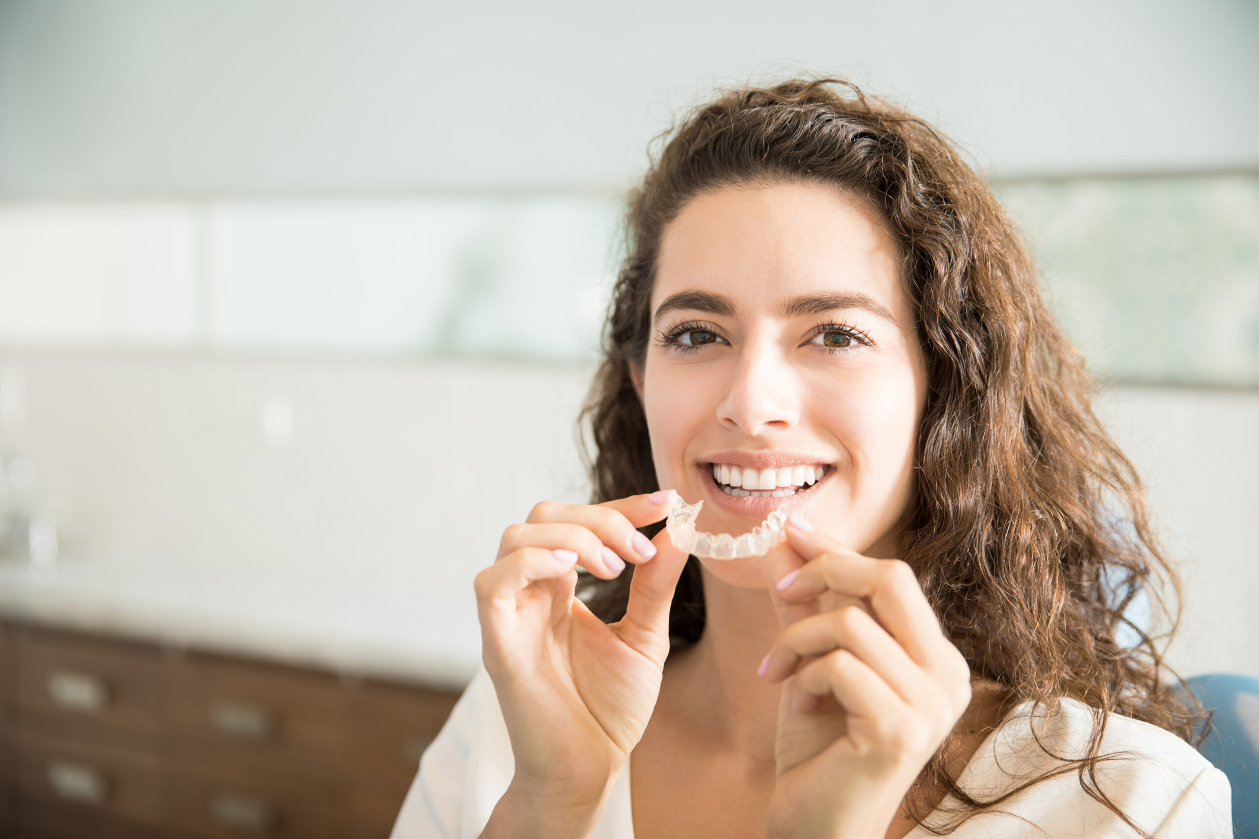 smiling young woman putting in her clear aligners
