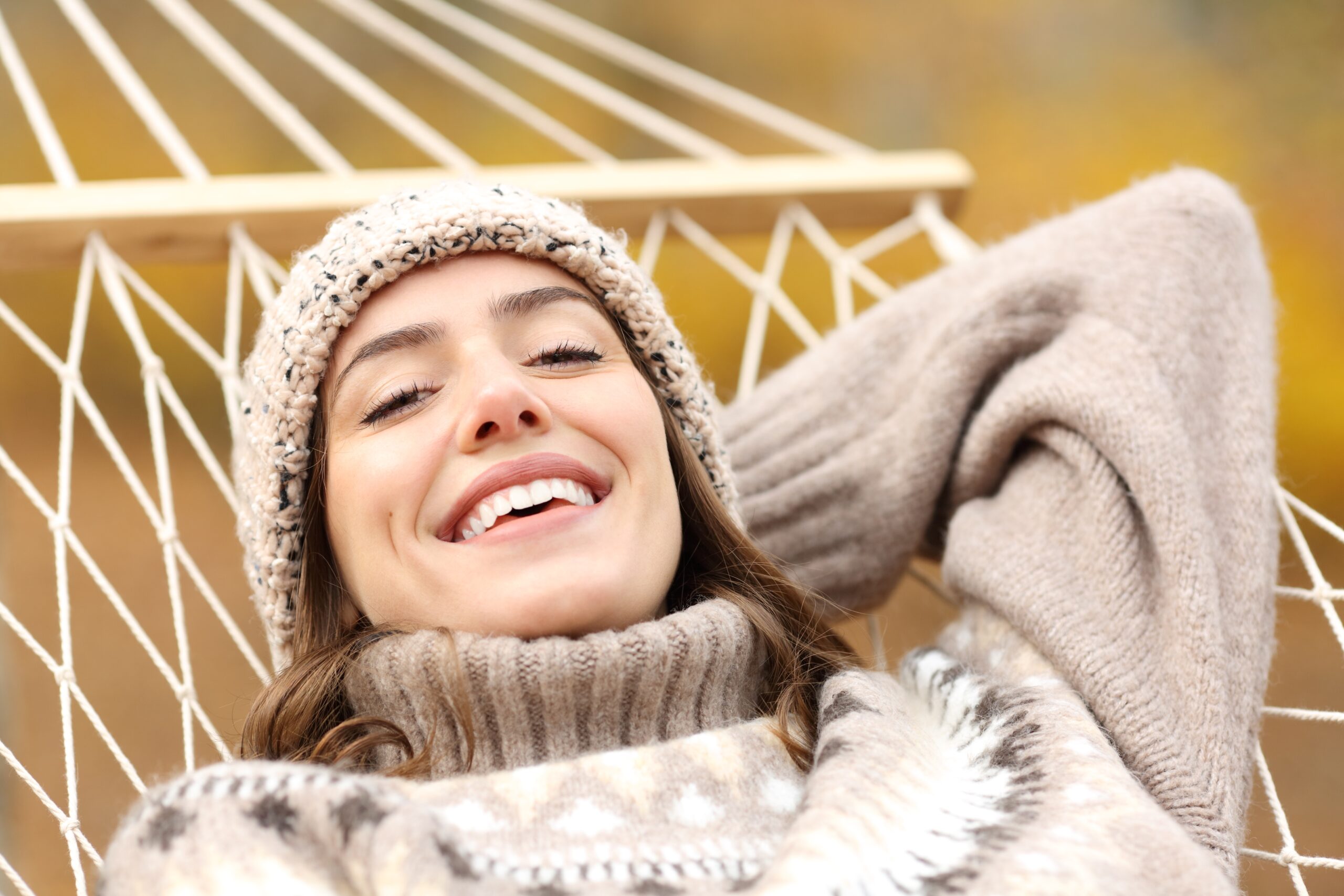 happy young woman smiling on a hammock, perfect white teeth