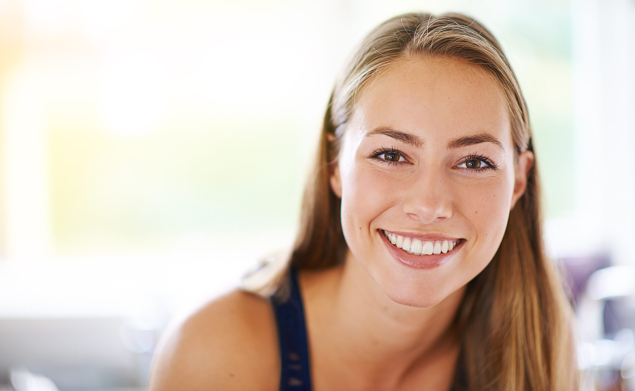 Portrait of a young woman relaxing at home in her living room, smiling, perfect white teeth